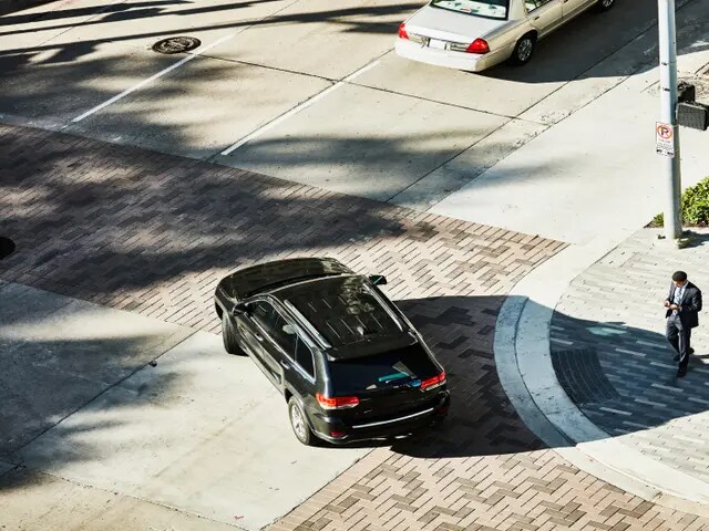 Vista aérea de un SUV negro de lujo que sale de una entrada.